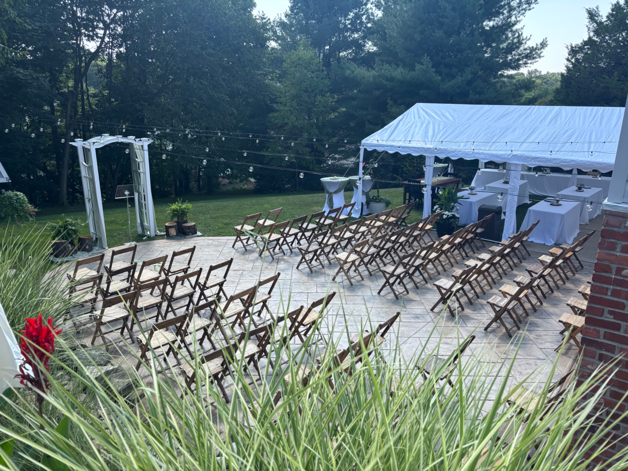 Wooden folding chairs arranged for an outdoor ceremony beside a white tent