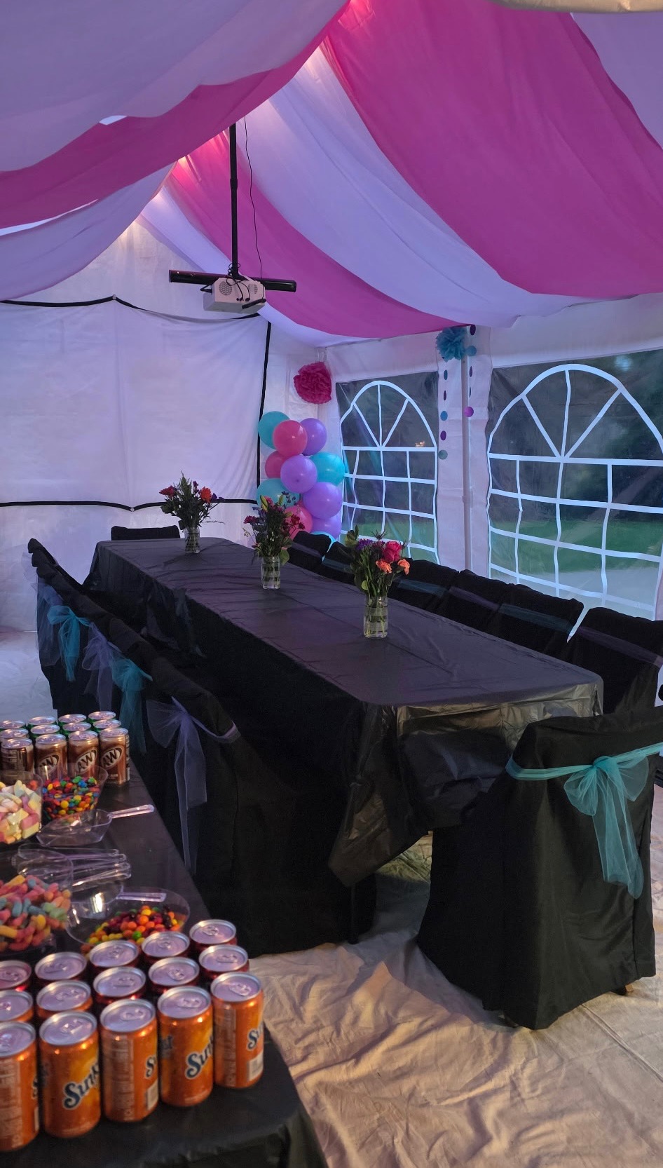 Pink and white draped party tent with black-covered tables and chairs
