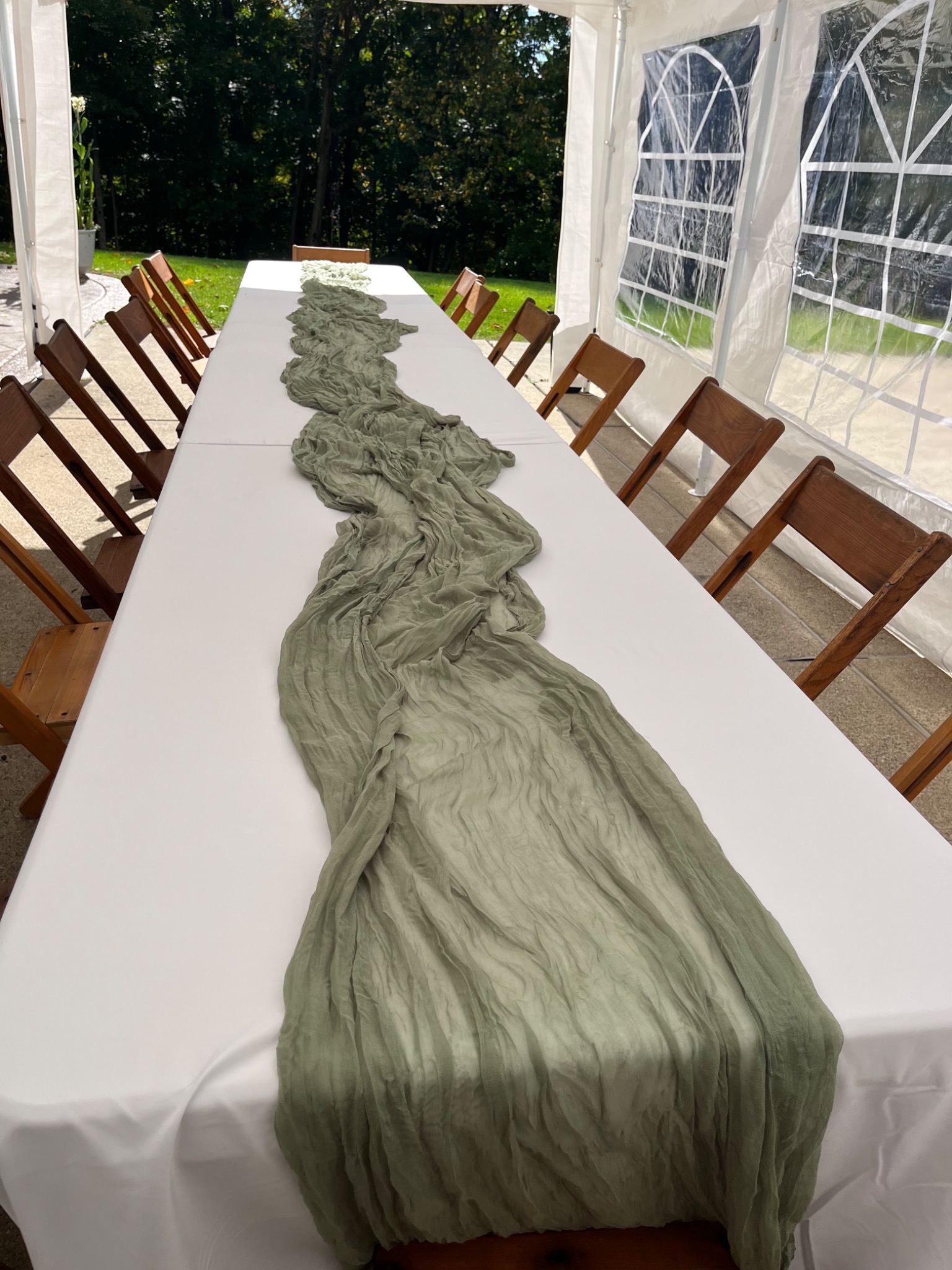 Long table dressed with a white linen and sage runner inside a tent
