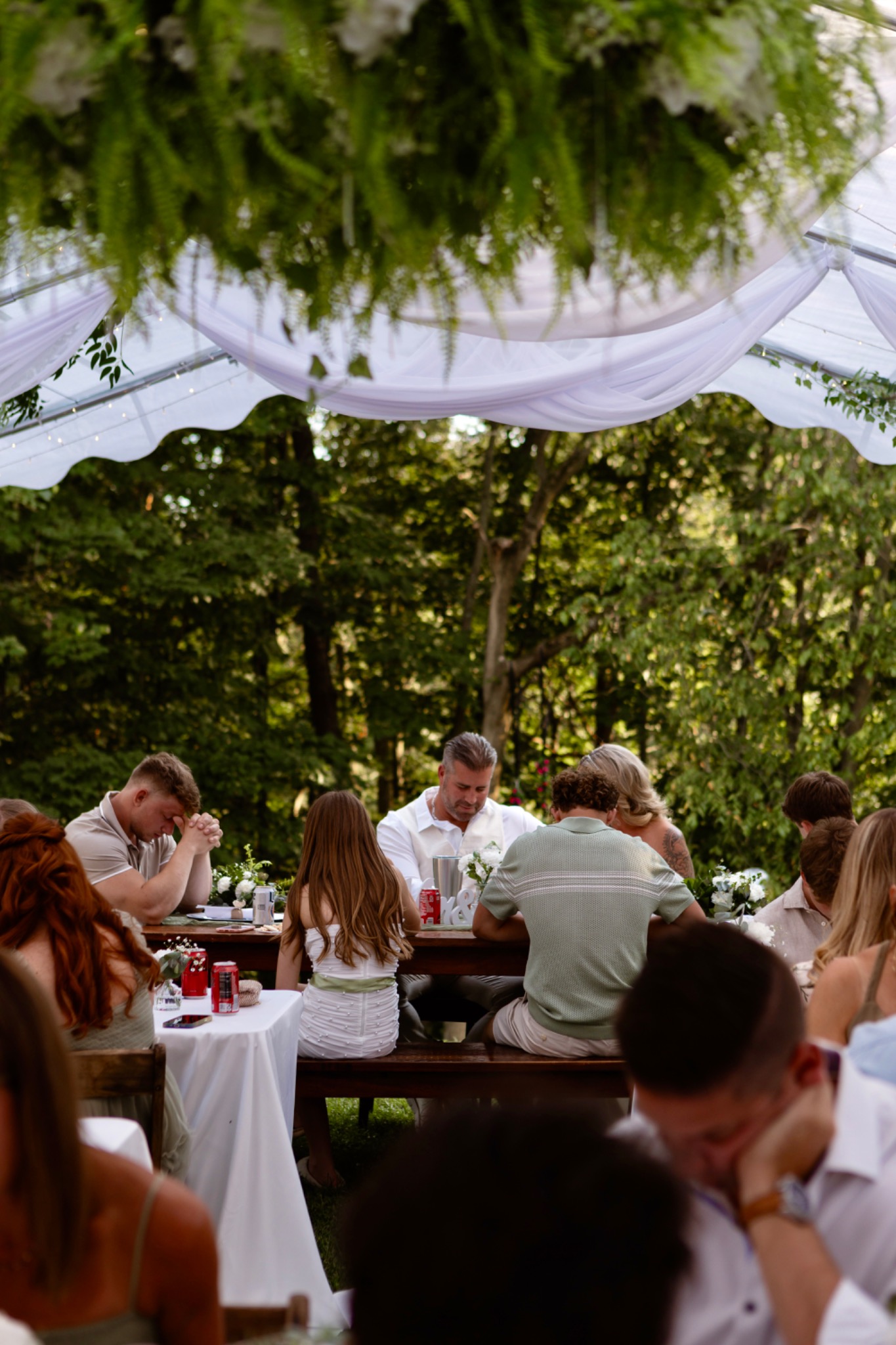 Guests sharing a meal beneath a draped tent with hanging greenery