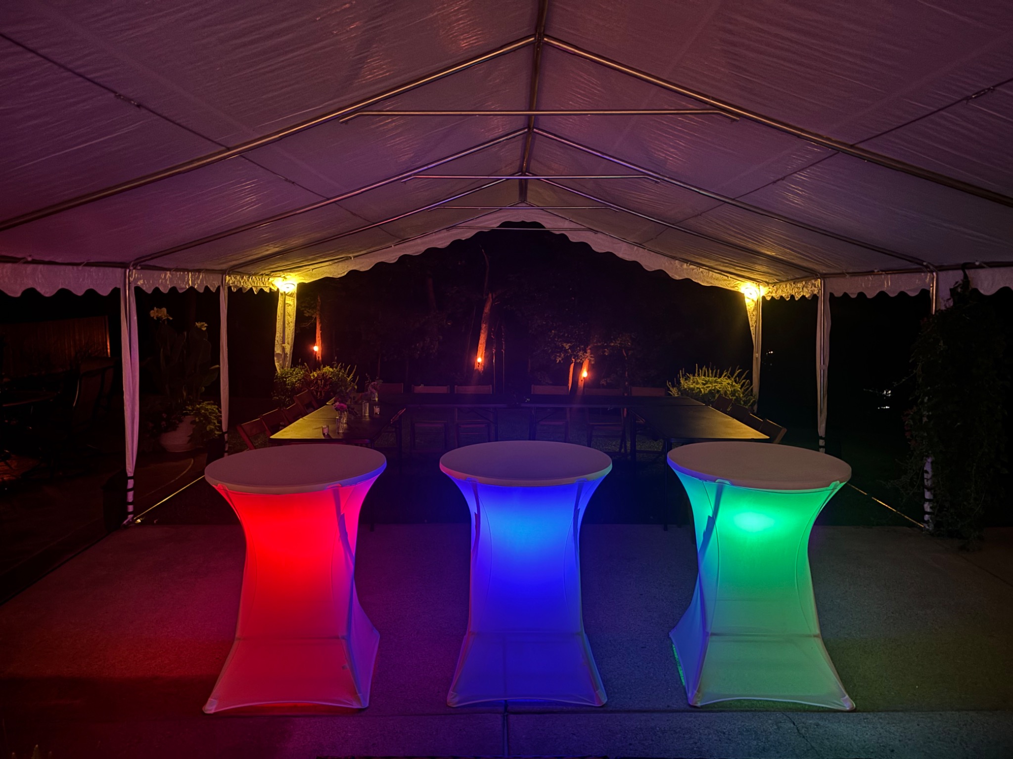 Three cocktail tables glowing beneath a tent